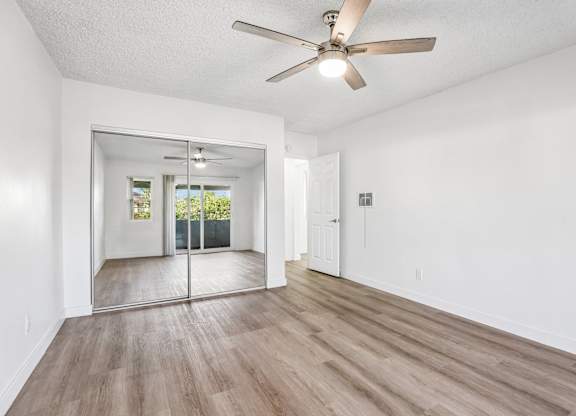 A room with a ceiling fan and sliding glass doors.