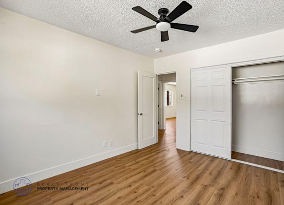 A spacious room with a ceiling fan and wooden flooring.
