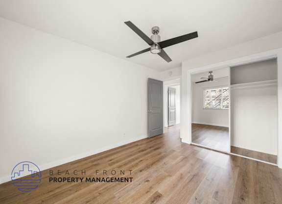 A room with a ceiling fan and wooden flooring.