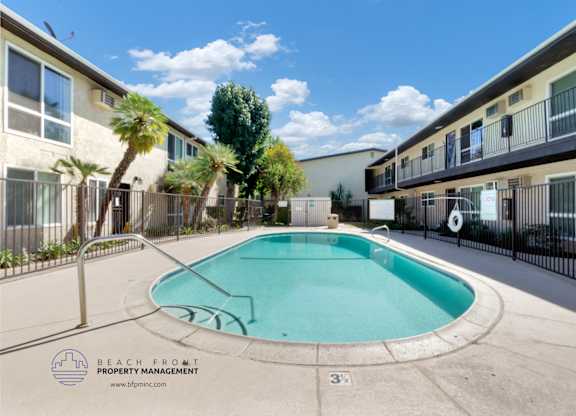 A pool surrounded by a fence and apartment buildings.