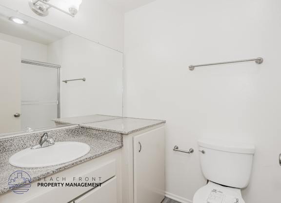 A white toilet sits next to a white sink in a small bathroom.