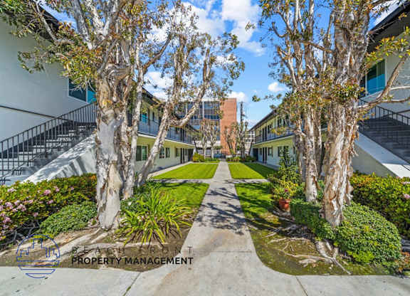 a courtyard between two buildings with trees and grass