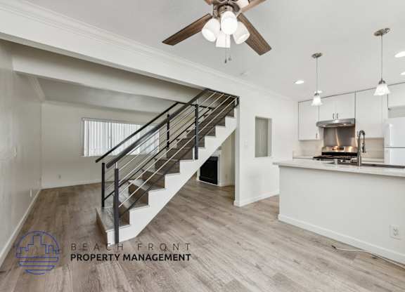 A spacious room with a staircase and a kitchen area.