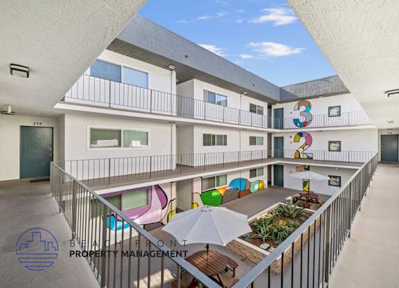 A courtyard with a white fence and a white umbrella.