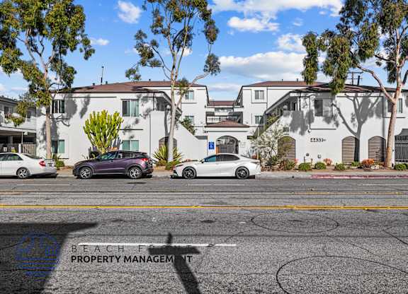 A street view with cars and apartment buildings.