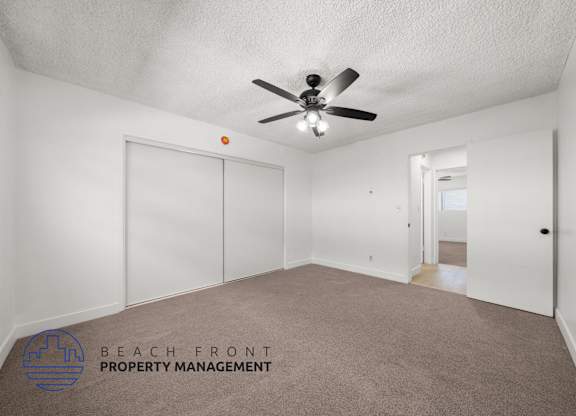 A spacious room with a ceiling fan and carpeted floor.
