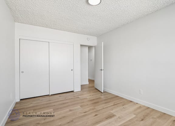 A white room with wooden floors and two doors.
