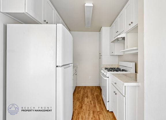 A kitchen with white appliances and cabinets.