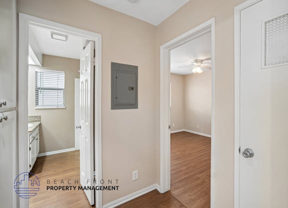 A hallway with a door on the right and a mirror on the left.