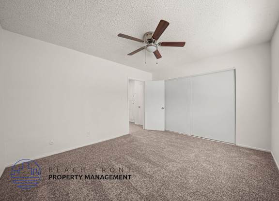 A room with a ceiling fan and carpeted floor.