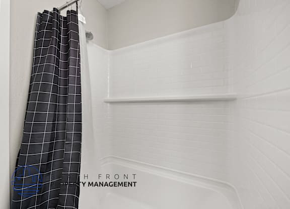A white bathroom with a shower curtain and a sign that says "Front".