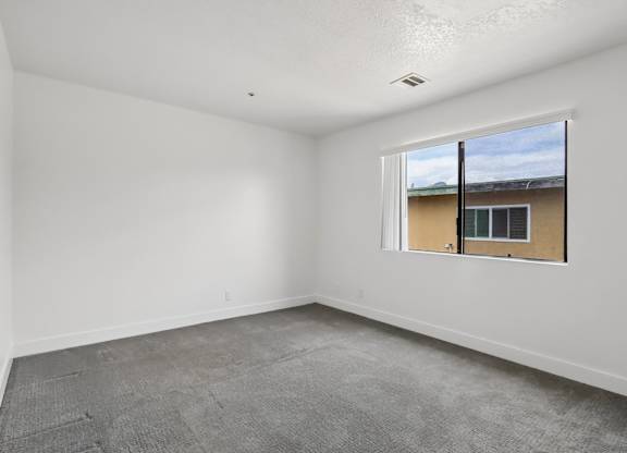 A room with a window and a view of a building outside.