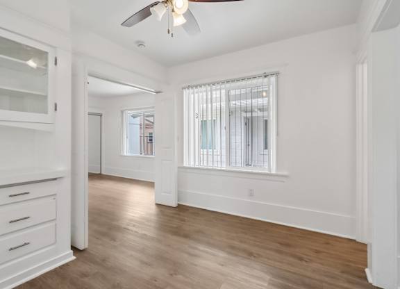 A room with a ceiling fan and a window with blinds.