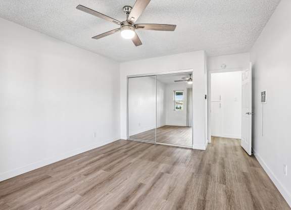 A room with a ceiling fan and wooden flooring.