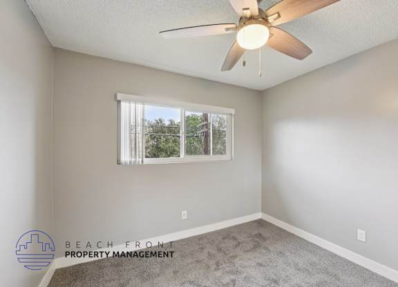 A room with a ceiling fan and a window with blinds.