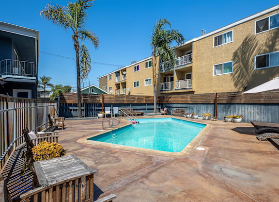 A pool surrounded by a patio and apartment buildings.