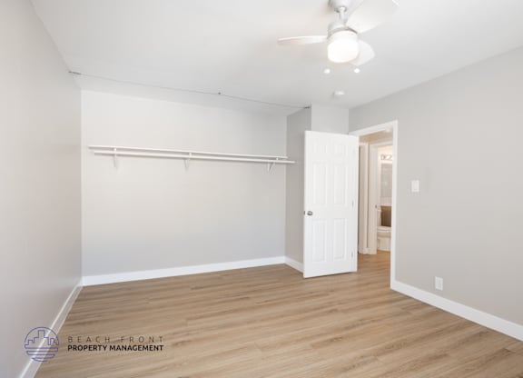 A room with a white ceiling fan and wooden flooring.