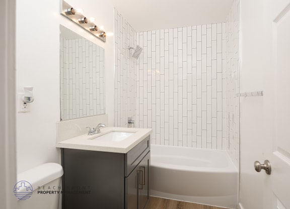 A white bathroom with a black cabinet and a white sink.