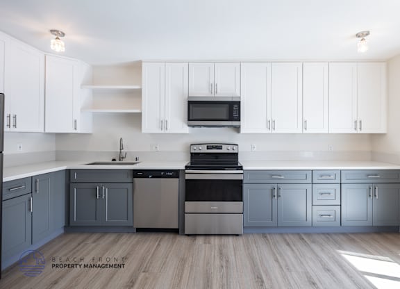 A kitchen with white cabinets and a wooden floor.
