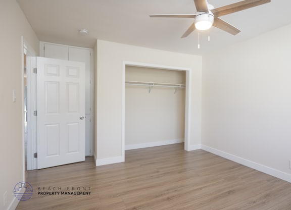 A room with a ceiling fan and a door on the left side.