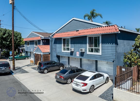 A blue house with a red roof and a sign that says Beach Front Property Management.