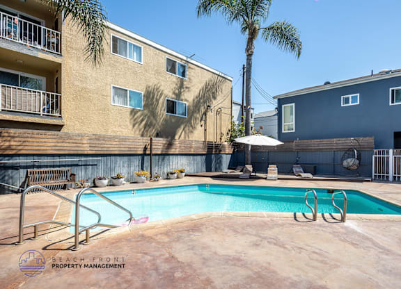 A pool surrounded by a metal fence and a building with a balcony.