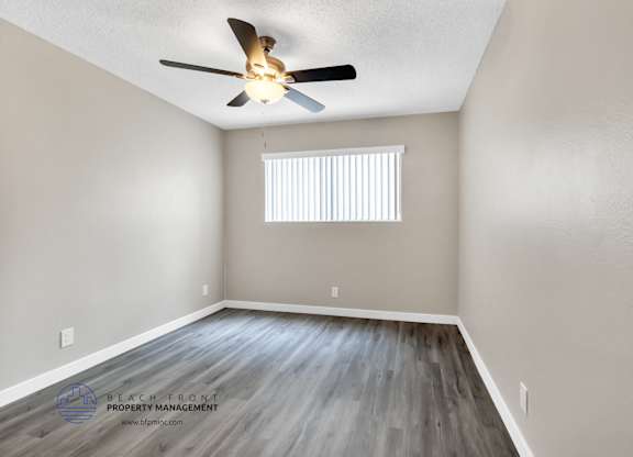 A room with a ceiling fan and a window with blinds.
