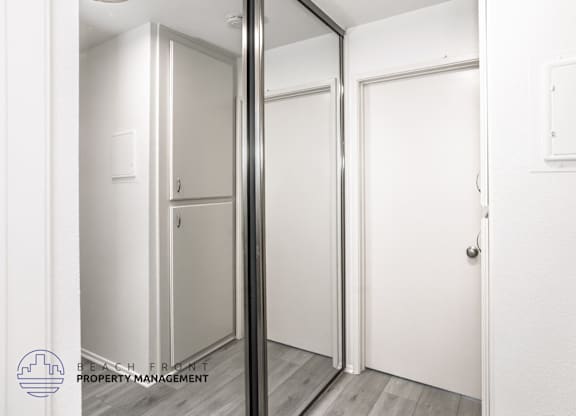 A white door is in a room with a mirror on the wall.