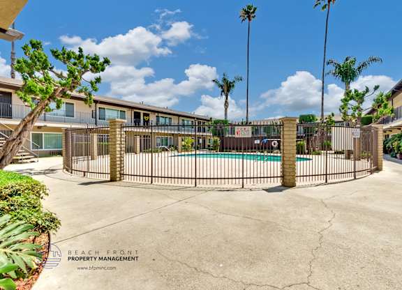 A pool surrounded by a fence with palm trees in the background.