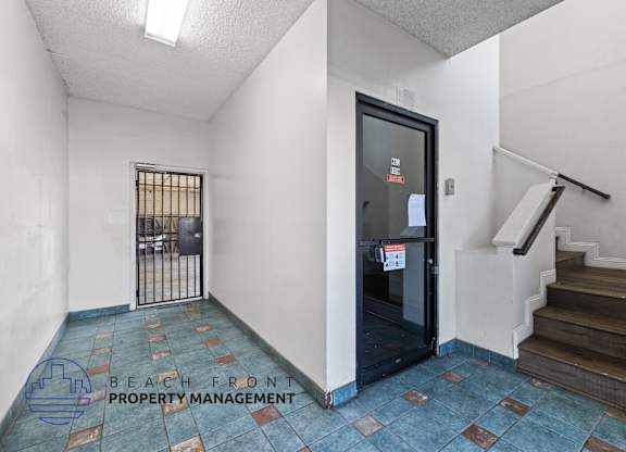 the entrance to the lobby of a building with stairs and a glass door