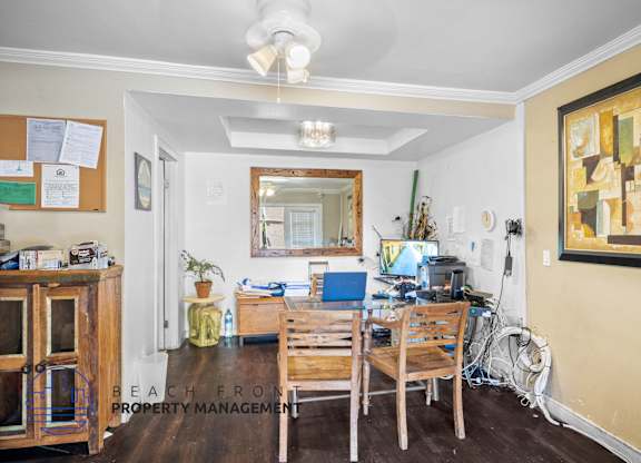 A room with a wooden table and chairs, a mirror, and a painting on the wall.