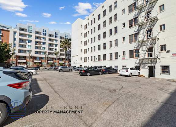 A parking lot with cars and a building with a fire escape.
