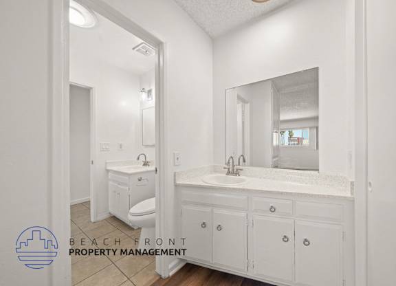 A bathroom with a sink, toilet, and mirror.