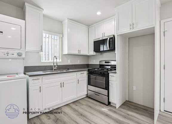 A kitchen with white cabinets and appliances, including a refrigerator, dishwasher, and oven.