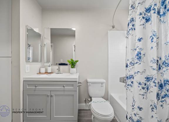 A bathroom with a white toilet, sink, and shower curtain.