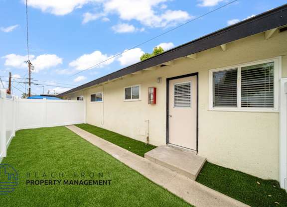 A white building with a green lawn in front.