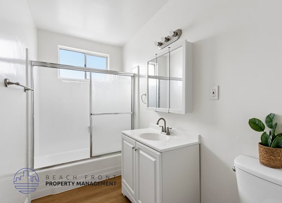 A white bathroom with a sink, mirror, and bathtub.