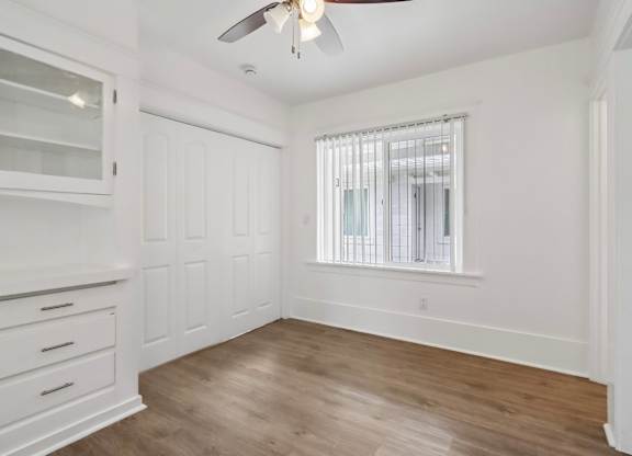 A room with a ceiling fan and a window with blinds.