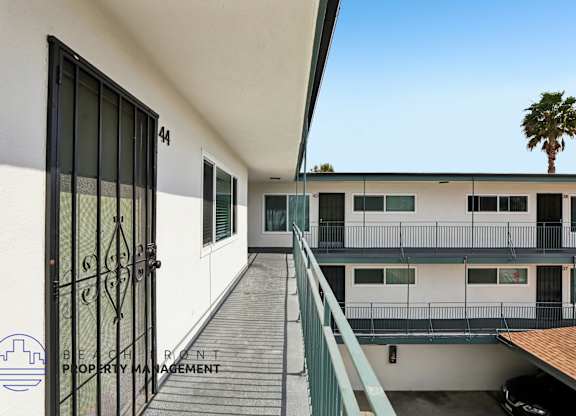 A balcony with a black gate and a building with the number 44 on it.