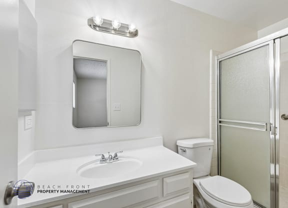 A white bathroom with a sink, toilet and shower.