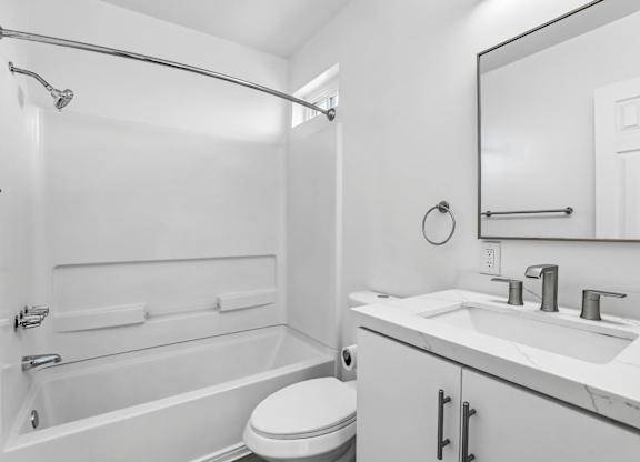 A white bathroom with a toilet, sink, and bathtub.