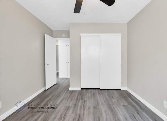 A room with a white door and a ceiling fan.