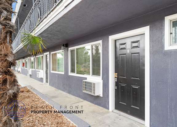 A building with a black door and windows with shutters.