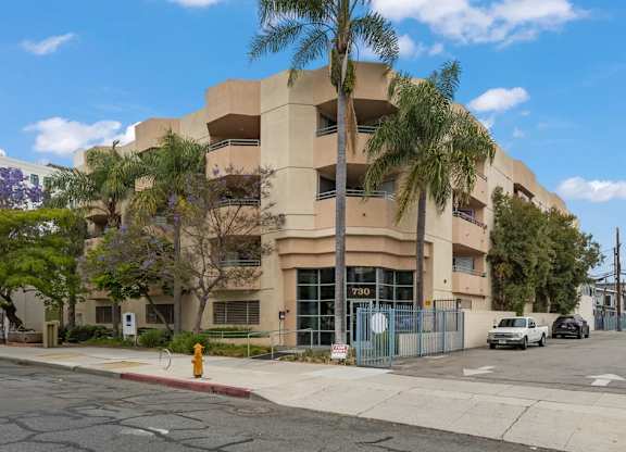 an apartment building with palm trees and a yellow fire hydrant