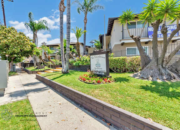 A sign for The Heights Apartments is in front of a tree.