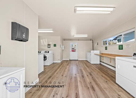 A laundry room with washers and dryers, a bench, and a sign for Beach Front Property Management.