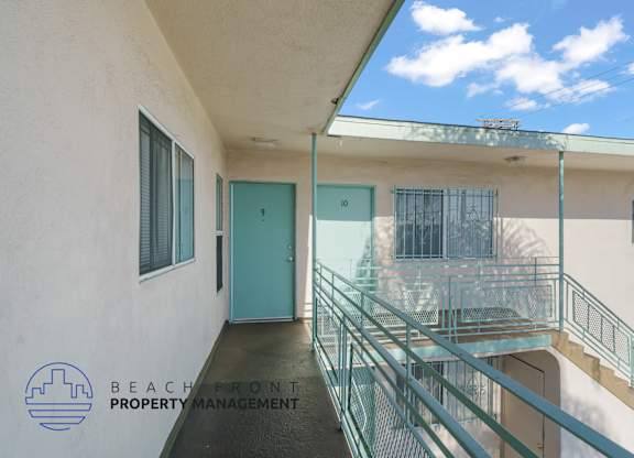 A balcony with a glass railing and a blue door.
