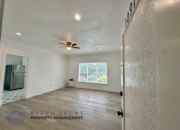 A room with a ceiling fan and a window overlooking a street.