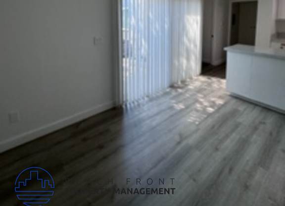 A room with wooden flooring and a window with curtains.