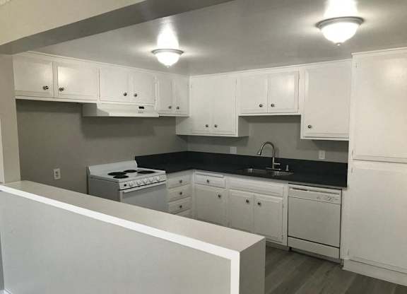 A kitchen with white cabinets and a black countertop.